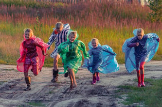 enfants blonds en coupes-pluie de couleurs en train de courir