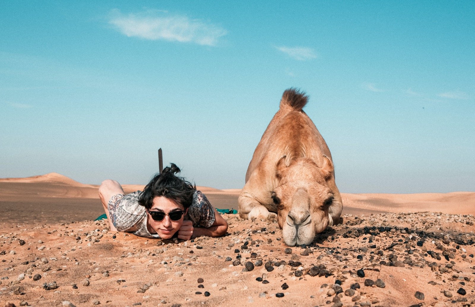 photo d'une personne et d'un dromadaire allongés dans le désert